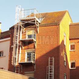 Brandevacuatie bordes en kooiladder aan de achterkant van een appartementsgebouw.