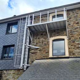 Op maat gemaakt balkon gebruikt met een uitklapbare ladder op een oude gevelmuur om te evacueren vanuit het raam van een huis.