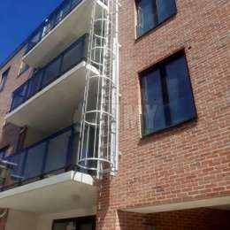 Uitschuifbare ladder met kooi voor brandevacuatie vanaf de balkons van een modern flatgebouw.