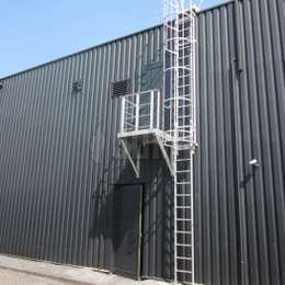 Balkonplatform met zijtoegang tot een kooiladder en gebruikt vanaf een deur op de 1e verdieping van een fabrieksgebouw met metalen bekleding.