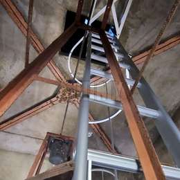 Kooiladder voor toegang tot een mangat in een kerktoren en weg van de muur geïnstalleerd met speciale bevestigingbeugels.