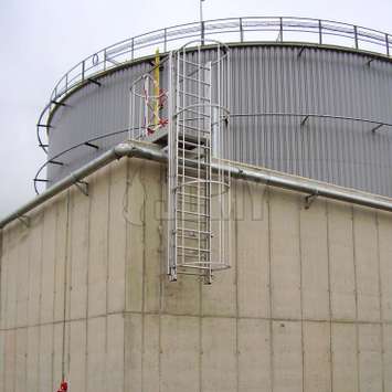 Uitschuifbare veiligheidsladder gebruikt voor het oversteken van een beschermingsmuur in een petroleumfabriek.