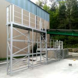 Vast toegangsplatform met twee niveaus, vaste ladders en leuningen, gebruikt voor toegang tot vrachtwagenaanhangers en ladingen.