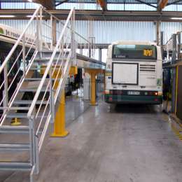 Verstelbaar loopbrugplatform met trappen voor busonderhoud.