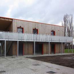 Voetgangersbrug bevestigd aan de gevel en rustend op palen Voetgangersbrug bevestigd aan de muur en rustend op steunpilaren; gebruikt voor toegang tot het gebouw langs de gevel.
