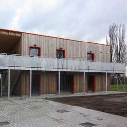 Voetgangersbrug bevestigd aan de muur en rustend op steunpilaren; gebruikt voor toegang tot het gebouw langs de gevel.