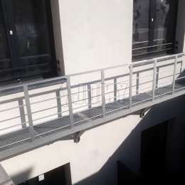 Voetgangersbrug bevestigd aan de muur en dienend als een evacuatiebalkon Aluminium gangpad bevestigd aan de muur en gebruikt als een brandtrapbalkon.